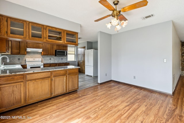 kitchen featuring tasteful backsplash, sink, ceiling fan, light hardwood / wood-style floors, and white appliances