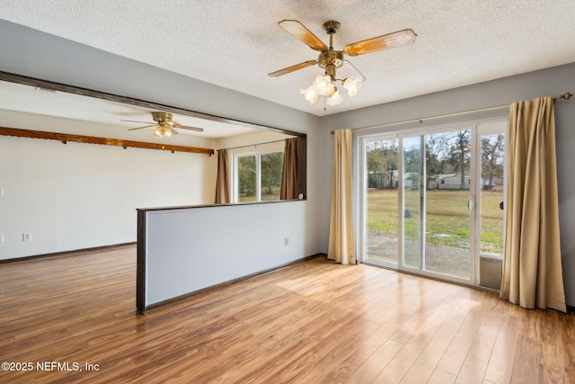 spare room with ceiling fan, a wealth of natural light, a textured ceiling, and light hardwood / wood-style flooring