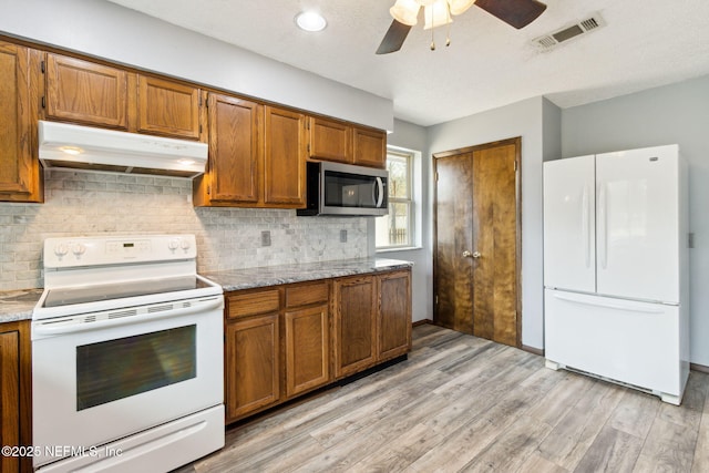 kitchen with tasteful backsplash, light stone counters, light hardwood / wood-style flooring, ceiling fan, and white appliances