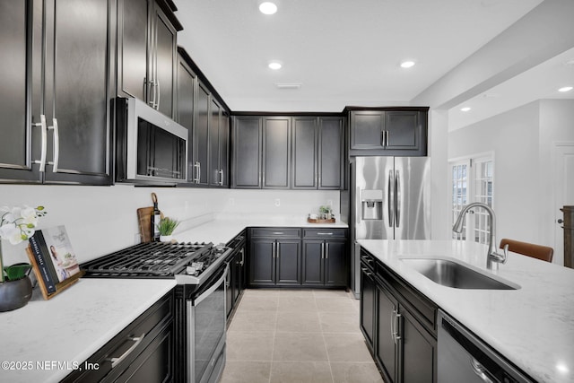 kitchen with light stone counters, stainless steel appliances, sink, and light tile patterned floors