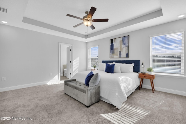 carpeted bedroom with connected bathroom, ceiling fan, and a tray ceiling