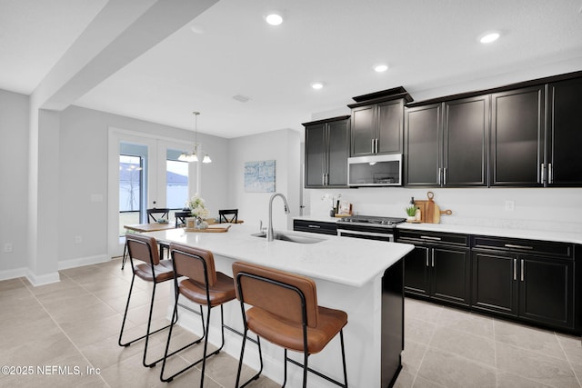 kitchen with sink, a breakfast bar area, a kitchen island with sink, stainless steel appliances, and decorative light fixtures