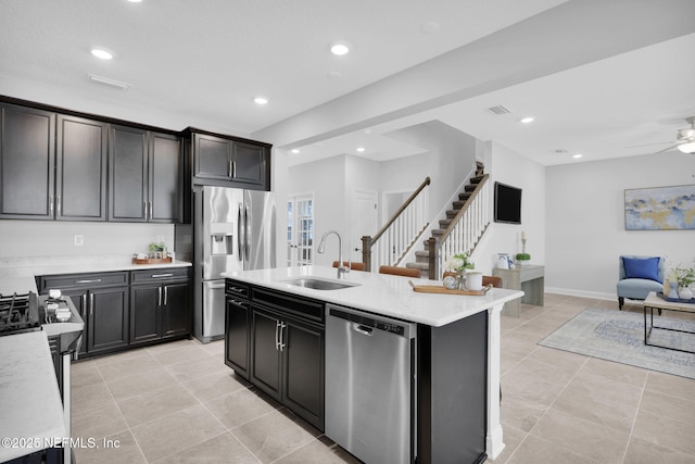 kitchen featuring sink, light tile patterned floors, ceiling fan, appliances with stainless steel finishes, and an island with sink