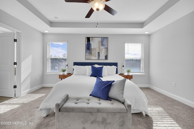 bedroom featuring multiple windows, ceiling fan, and a tray ceiling