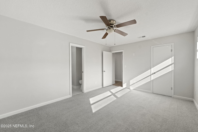 unfurnished bedroom featuring light carpet, connected bathroom, a textured ceiling, and ceiling fan