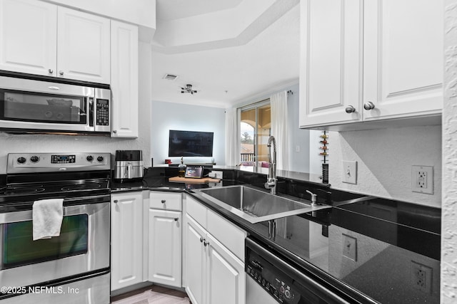 kitchen featuring sink, white cabinets, appliances with stainless steel finishes, and kitchen peninsula