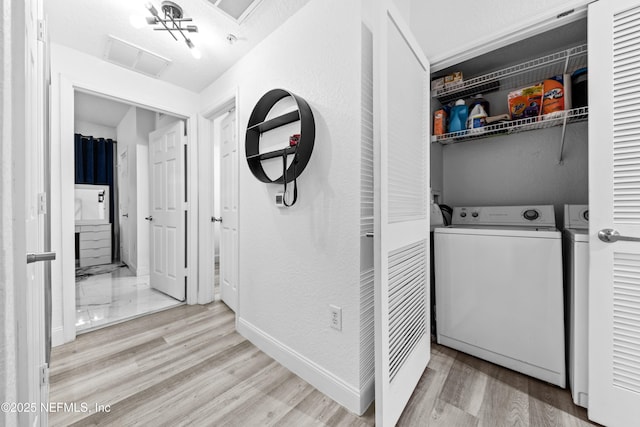 washroom featuring light hardwood / wood-style flooring, separate washer and dryer, and a textured ceiling