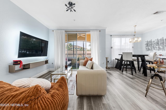 living room with light hardwood / wood-style flooring, an inviting chandelier, and crown molding