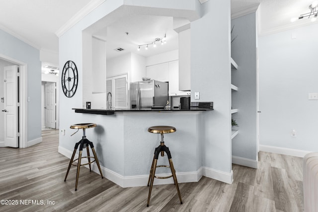 kitchen featuring stainless steel fridge with ice dispenser, kitchen peninsula, white cabinetry, and crown molding