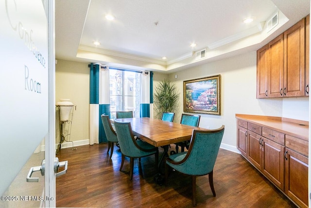 dining room featuring ornamental molding, dark wood-type flooring, and a raised ceiling