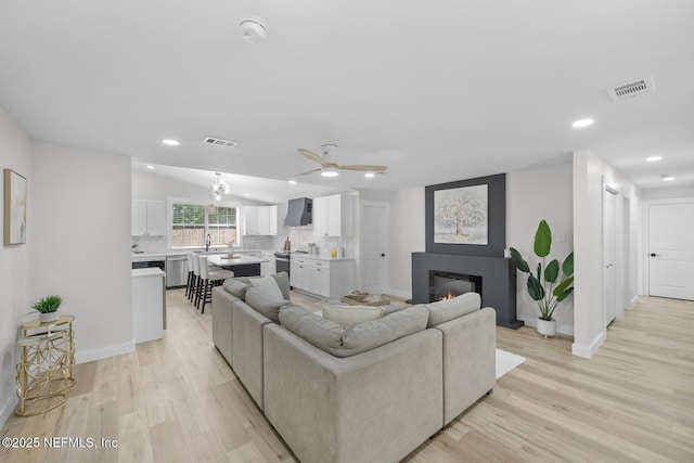 living room with vaulted ceiling, light hardwood / wood-style floors, and ceiling fan