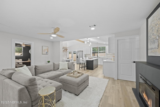 living room featuring ceiling fan, lofted ceiling, sink, and light hardwood / wood-style floors