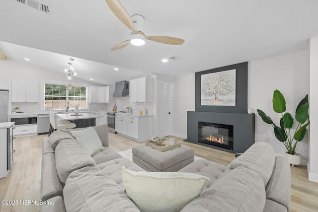 living room with vaulted ceiling, light hardwood / wood-style floors, and ceiling fan