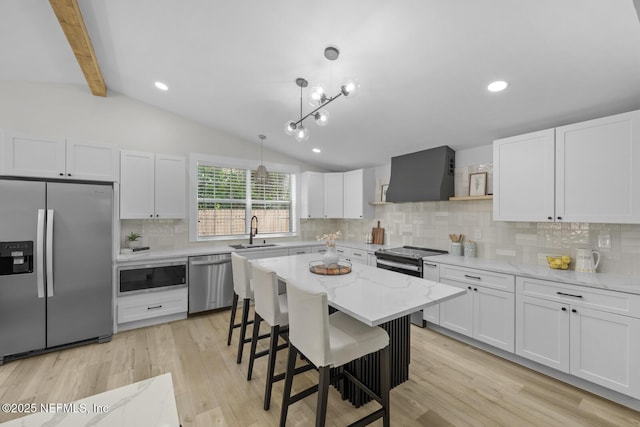 kitchen with wall chimney exhaust hood, sink, white cabinetry, decorative light fixtures, and stainless steel appliances