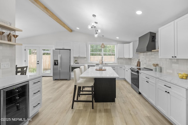 kitchen featuring wine cooler, wall chimney exhaust hood, a center island, stainless steel appliances, and white cabinets