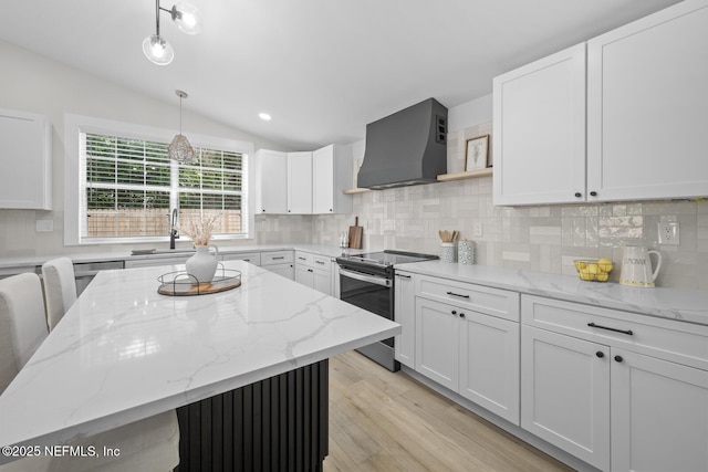 kitchen with pendant lighting, stainless steel electric range, premium range hood, white cabinetry, and light stone countertops