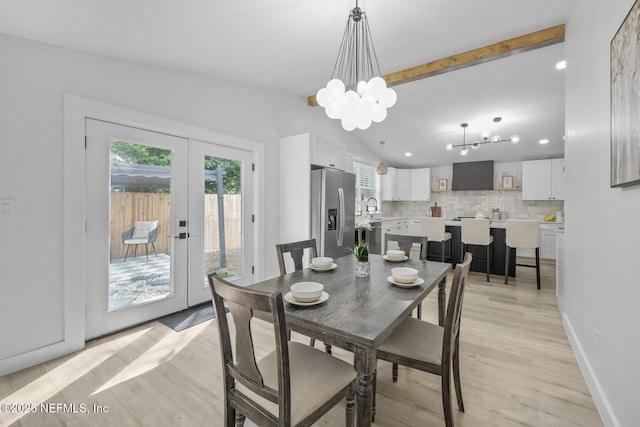 dining area featuring french doors, sink, vaulted ceiling with beams, light wood-type flooring, and a notable chandelier