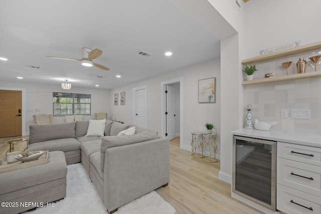 living room with ceiling fan, indoor bar, wine cooler, and light hardwood / wood-style floors