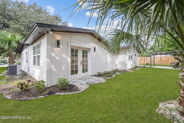 exterior space with french doors, central AC unit, and a lawn