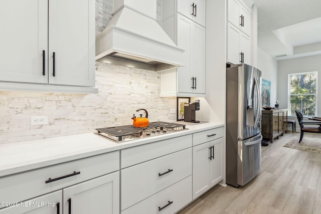 kitchen with white cabinets, custom exhaust hood, appliances with stainless steel finishes, and tasteful backsplash