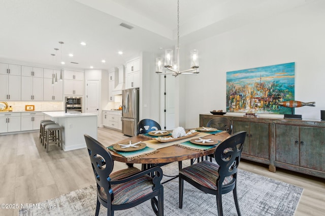 dining space with light hardwood / wood-style floors, sink, and an inviting chandelier