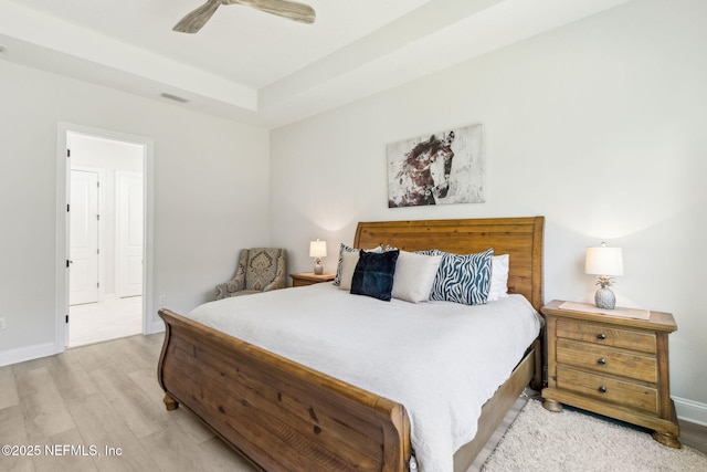 bedroom with ceiling fan, a raised ceiling, and light hardwood / wood-style flooring