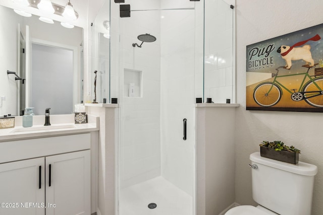 bathroom featuring toilet, a shower with shower door, and vanity