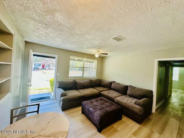 living room featuring ceiling fan, hardwood / wood-style floors, and a textured ceiling