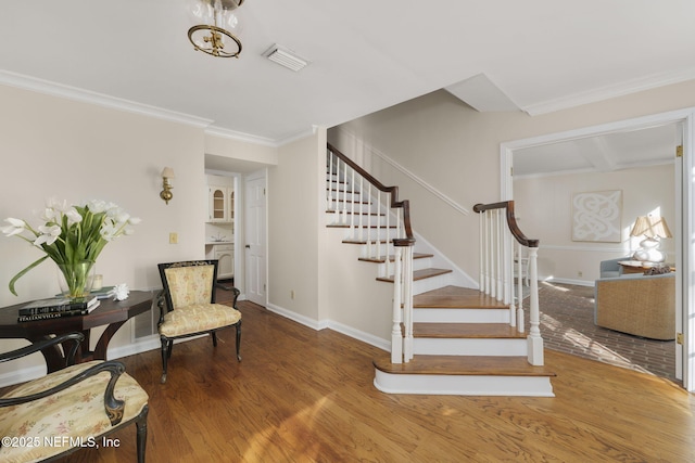 stairs with hardwood / wood-style flooring and crown molding