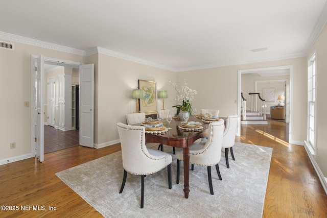 dining space featuring wood-type flooring and ornamental molding