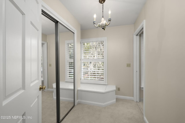 hall featuring a notable chandelier and light colored carpet