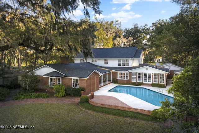 rear view of house featuring french doors, a patio, and a lawn