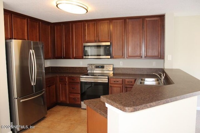 kitchen featuring sink, light tile patterned flooring, kitchen peninsula, and appliances with stainless steel finishes