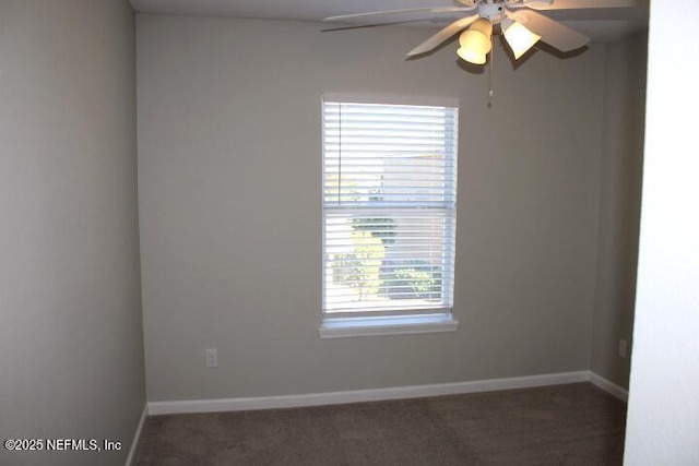 empty room with ceiling fan, a healthy amount of sunlight, and dark colored carpet