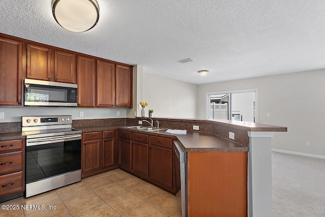 kitchen with stainless steel appliances, sink, a textured ceiling, and kitchen peninsula