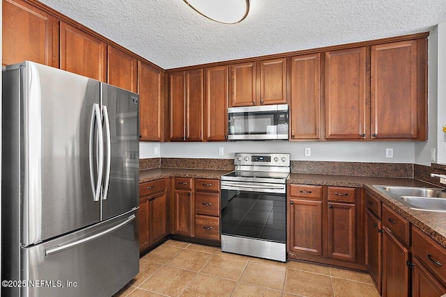 kitchen featuring stainless steel appliances, light tile patterned flooring, sink, and a textured ceiling