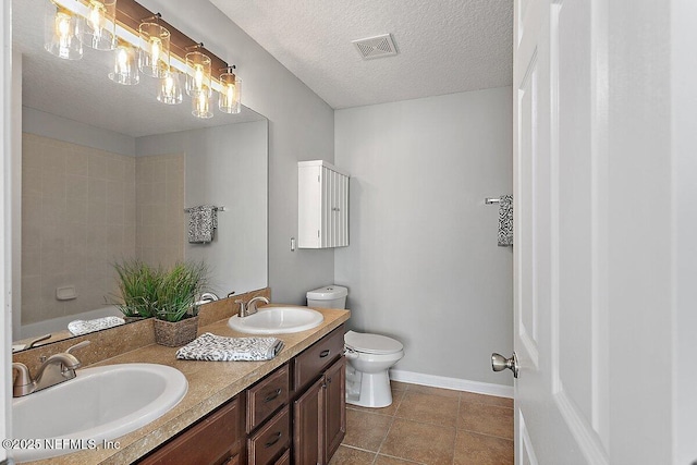 bathroom featuring vanity, a textured ceiling, tile patterned floors, and toilet