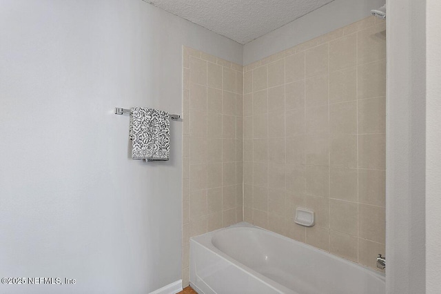 bathroom featuring tiled shower / bath and a textured ceiling