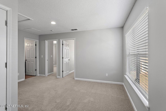 empty room with light colored carpet and a textured ceiling