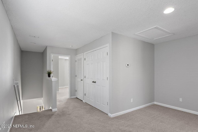 spare room featuring light carpet and a textured ceiling