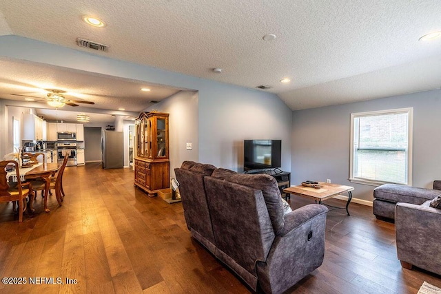 living room featuring ceiling fan, a textured ceiling, dark hardwood / wood-style floors, and lofted ceiling