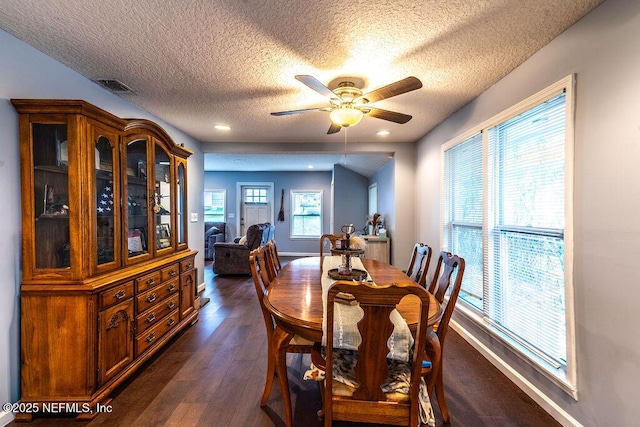 dining area featuring ceiling fan, dark wood-type flooring, and a textured ceiling