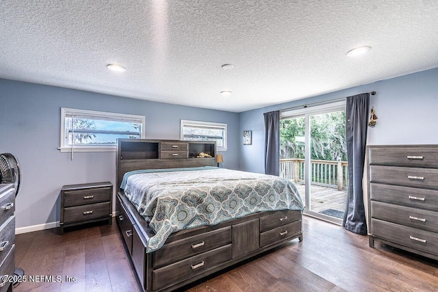 bedroom featuring multiple windows, a textured ceiling, dark hardwood / wood-style floors, and access to outside