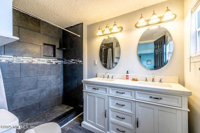 bathroom featuring a tile shower, hardwood / wood-style flooring, toilet, a textured ceiling, and vanity