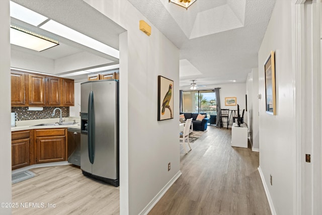 kitchen featuring tasteful backsplash, appliances with stainless steel finishes, sink, and light hardwood / wood-style flooring