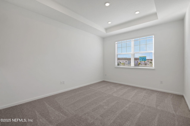 carpeted empty room featuring a tray ceiling