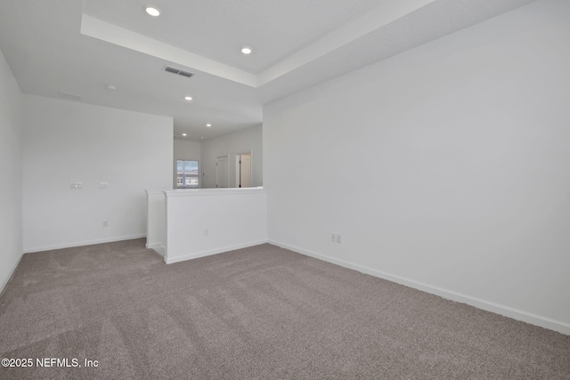 unfurnished room featuring a raised ceiling and carpet