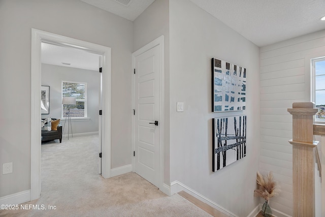 corridor featuring light carpet and a textured ceiling