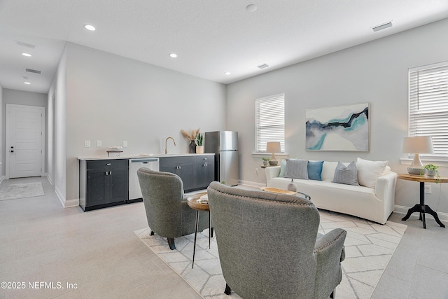 living room with light tile patterned floors, sink, a textured ceiling, and a wealth of natural light