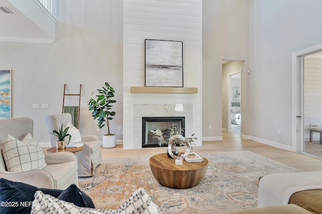 living room featuring a fireplace, light hardwood / wood-style floors, and a high ceiling